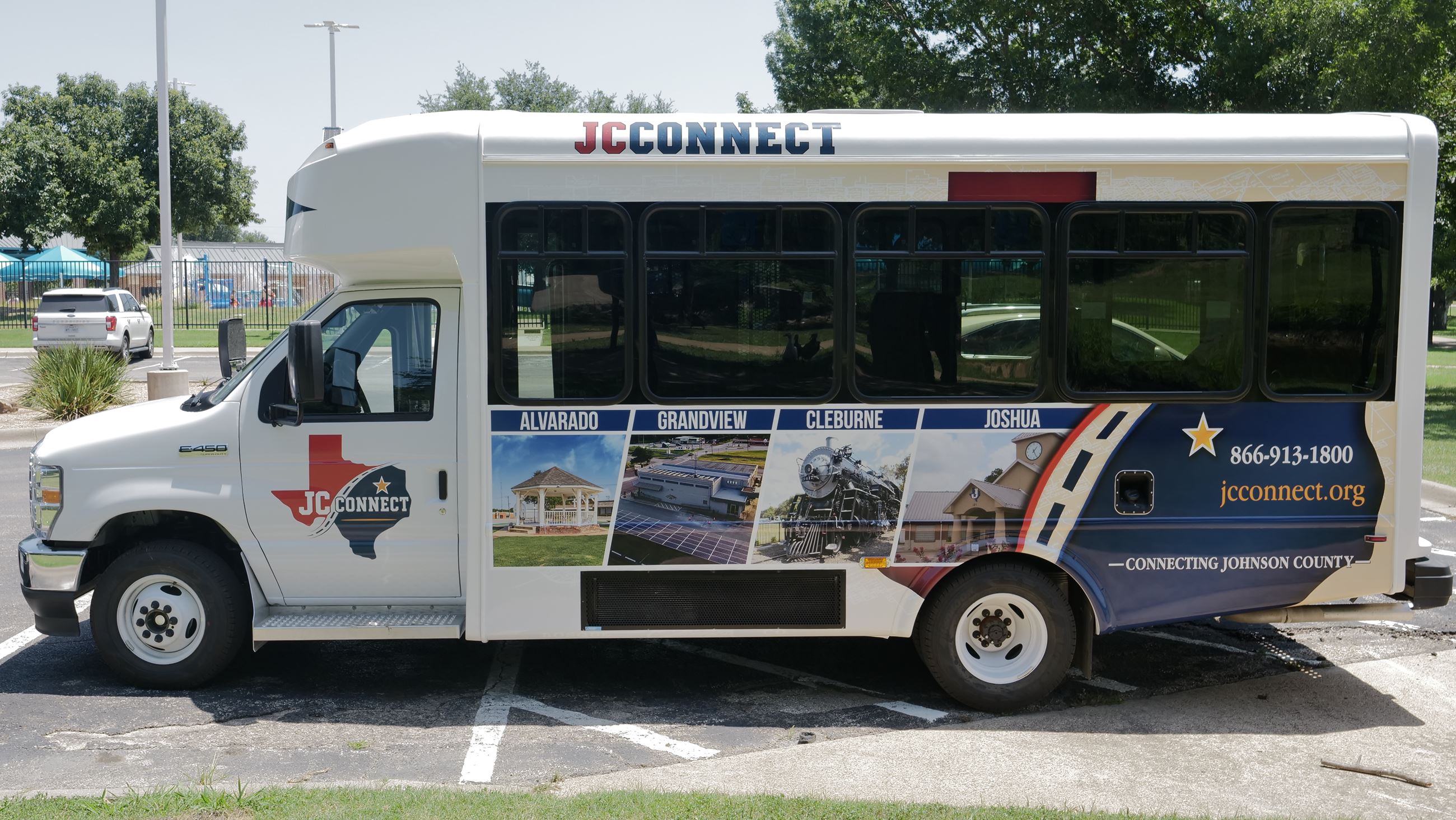 Photo of a small bus decorated with community photos, parked in a parking lot